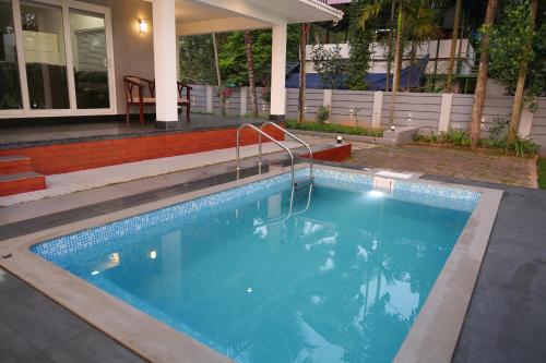 a swimming pool in front of a house at Serene Retreat in Cochin