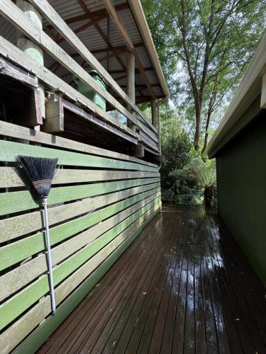 a wooden deck with a broom on the side of a house at Sassafras Treehouse Private home in the Dandenong Ranges, Victoria in Sassafras