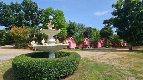 a fountain in a park with houses in the background at kkcc แก่งกระจานแคมป์ - ริมน้ำ รีสอร์ต in Kaeng Krachan
