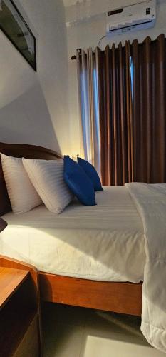 a bed with two blue pillows on top of it at Kandy Alpine Breeze in Kandy
