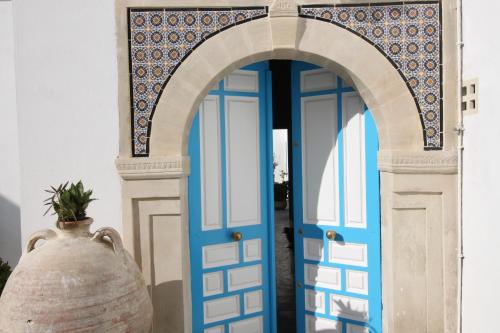 an archway with a blue door and a vase at Dar R'Bat, Maison d'Hôtes de charme in Nabeul