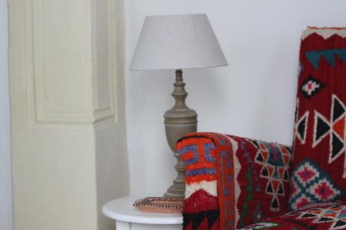 a lamp sitting on a table next to a couch at Dar R'Bat, Maison d'Hôtes de charme in Nabeul