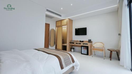 a white bedroom with a bed and a tv at The Healing Luxury Hotel in Buon Ma Thuot