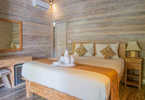 a bedroom with a bed with a stuffed animal on it at The Nichos Bungalows And Villas in Nusa Lembongan