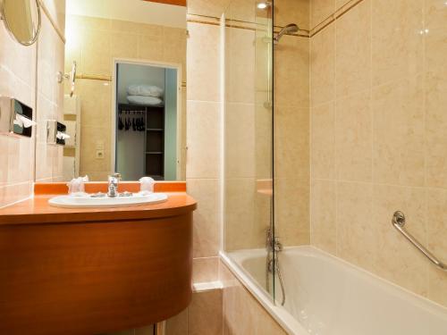 a bathroom with a sink and a bath tub at Hotel Kyriad Tours St Pierre des Corps Gare in Saint-Pierre-des-Corps