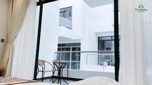 a bedroom with a balcony with a bed and two chairs at The Healing Luxury Hotel in Buon Ma Thuot