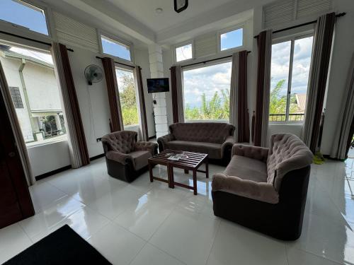 a living room with couches and a table and windows at Kandy Alpine Breeze in Kandy