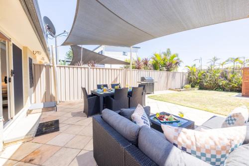 a patio with a couch and a table on a patio at 8 Ocean Avenue - Pet Friendly, Wi-Fi, views and Aircon in Anna Bay