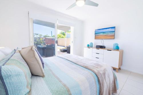 a bedroom with a bed and a tv on a wall at 8 Ocean Avenue - Pet Friendly, Wi-Fi, views and Aircon in Anna Bay