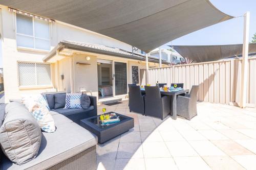 a patio with a couch and a table on a patio at 8 Ocean Avenue - Pet Friendly, Wi-Fi, views and Aircon in Anna Bay