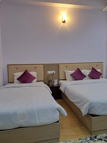 two beds in a hotel room with purple pillows at Best Southern Hotel in Kuākāta
