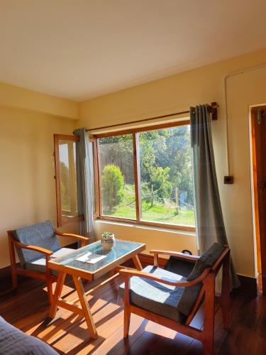 a living room with a table and chairs and a window at Simba Jungle Lodge, Binsar Wildlife Sanctuary in Binsar