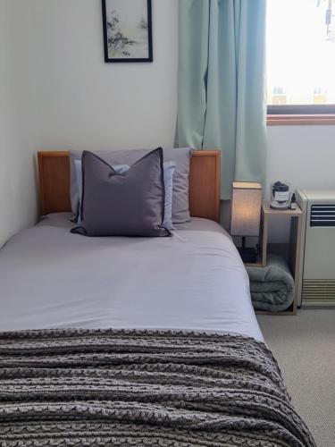 a bedroom with a bed with a pillow and a window at Silver Fox Madarao in Iiyama