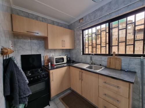 a small kitchen with a sink and a microwave at Sandalwood Property in Lusaka