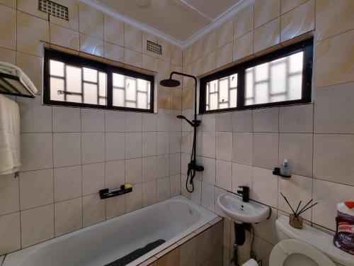 a bathroom with a tub and a sink and two windows at Sandalwood Property in Lusaka