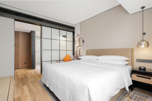 a bedroom with a large white bed with white pillows at Sheraton Chengdu Lido Hotel in Chengdu