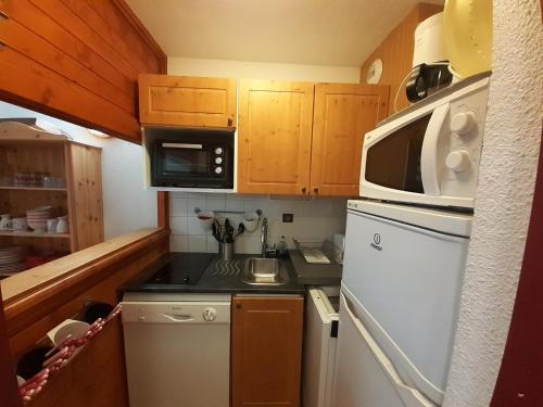 une petite cuisine avec une cuisinière et un micro-ondes dans l'établissement Studio en station avec balcon sud, proche remontées, Wi-Fi, parking gratuit - FR-1-561-136, à Modane
