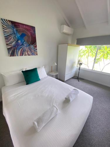 a bedroom with a white bed with two pillows on it at Daffys Beach House in Suffolk Park