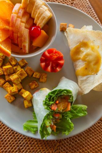 a plate of food with a sandwich and a bowl of fruit at Morgan Villas in El Nido