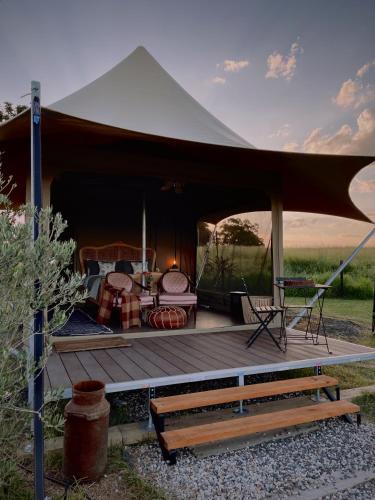 a tent with a deck with a table and chairs at The Forager Glamping at Twigley Farm in Marburg