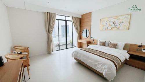 a bedroom with a bed and a desk and a window at The Healing Luxury Hotel in Buon Ma Thuot