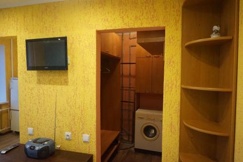 a room with a yellow wall with a tv and a washing machine at Apartament Erfolg 3 in Daugavpils