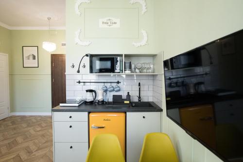 a kitchen with a sink and two yellow chairs at Petite Visite No 18A i 18B in Toruń