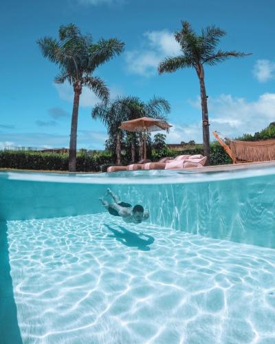 a person swimming in a swimming pool with palm trees at TAF Villas Beach Resort with Tesla in Tigaki