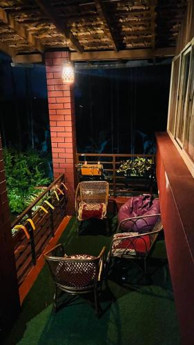 a balcony with chairs and a table and a window at Coorg Tribal Land homestay in Kushālnagar
