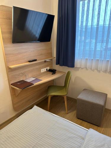a bedroom with a desk with a television and a chair at Hotel Am Vogelsanger Weg in Düsseldorf