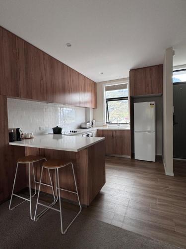 a kitchen with wooden cabinets and a white refrigerator at Queenstown Retreat in Queenstown