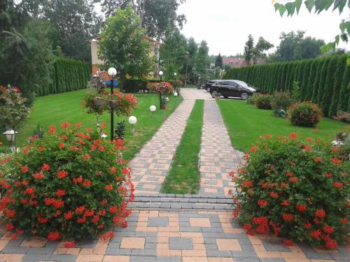 a garden with red flowers and a brick walkway at Alba Regia Pansion Egri in Jahodná
