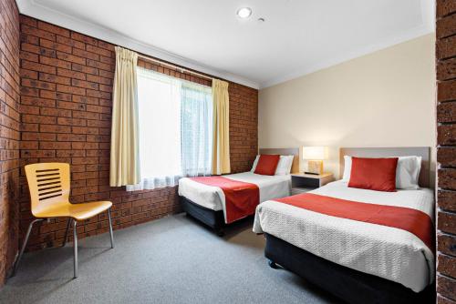 a hotel room with two beds and a brick wall at Bomaderry Motor Inn in Nowra