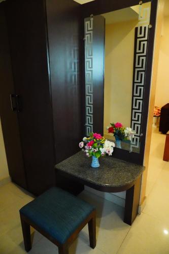 a table with a chair and a mirror and flowers at Vinayagam Residency in Arcot