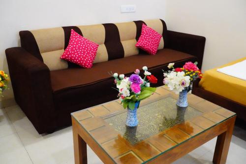 a living room with two vases with flowers on a table at Vinayagam Residency in Arcot