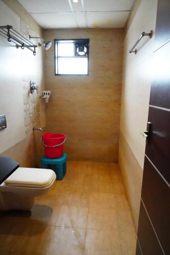 a bathroom with a toilet and a red bucket at Vinayagam Residency in Arcot