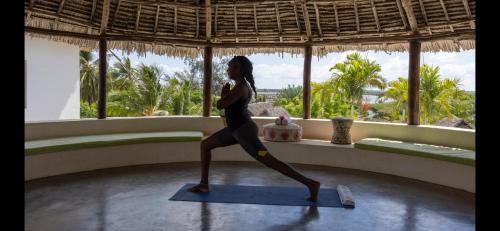 a woman doing a yoga pose in a room with a window at Dhow House in Shela