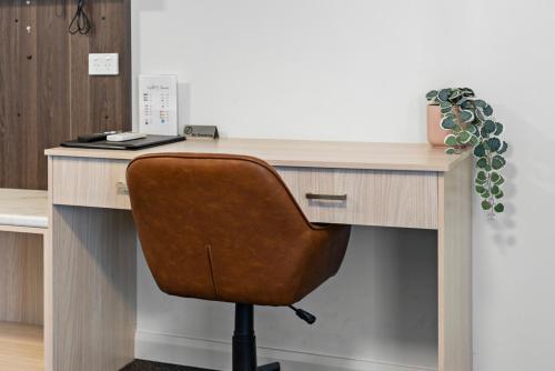 a wooden desk with a brown chair in front of it at Bomaderry Motor Inn in Nowra
