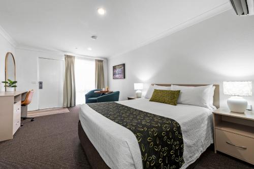 a hotel room with a large bed and a desk at Bomaderry Motor Inn in Nowra