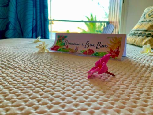 a pink flower on a bed with a sign on it at BLUE LAGOON - Terrace View & Beach Access - FREE WIFI PARKING - Bora Bora Dream - SPECIAL OFFER in Bora Bora