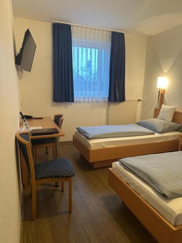 a hotel room with two beds and a desk and a chair at Hotel Am Vogelsanger Weg in Düsseldorf