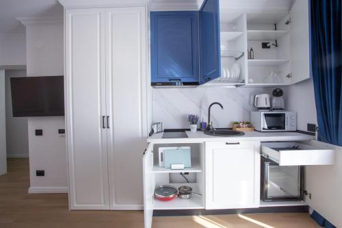 a white kitchen with blue cabinets and a sink at Crystal Luxury in Craiova