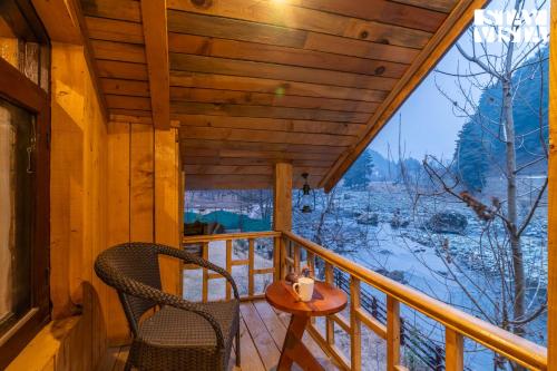 a cabin with two chairs and a table on a balcony at StayVista at Amanat with BBQ, WiFi in Pahalgām