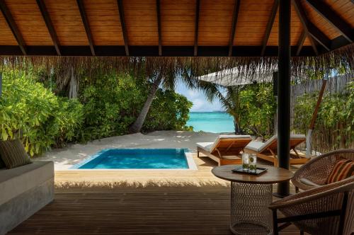 a resort with a swimming pool and a table and chairs at Velassaru Maldives in South Male Atoll