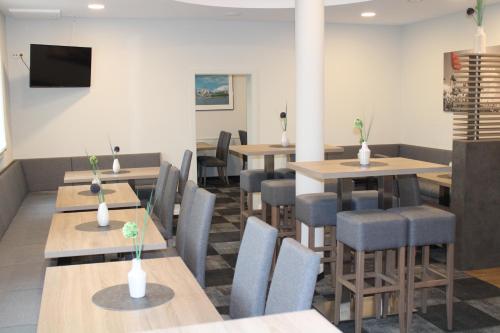 a restaurant with tables and chairs and a flat screen tv at Hotel Am Vogelsanger Weg in Düsseldorf