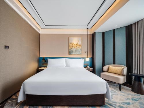 a bedroom with a large bed and a chair at Hilton Garden Inn Beijing Guomao in Beijing