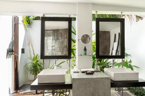 a bathroom with two sinks and two mirrors at Velassaru Maldives in South Male Atoll