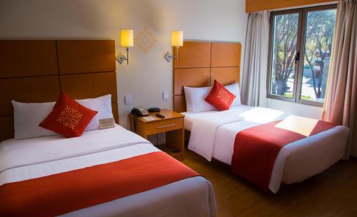 a hotel room with two beds and a window at Xima Exclusive Cusco in Cusco