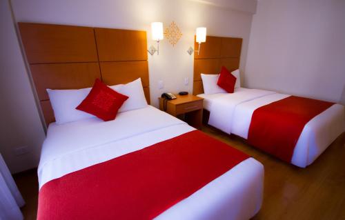 a hotel room with two beds with red and white sheets at Xima Exclusive Cusco in Cusco