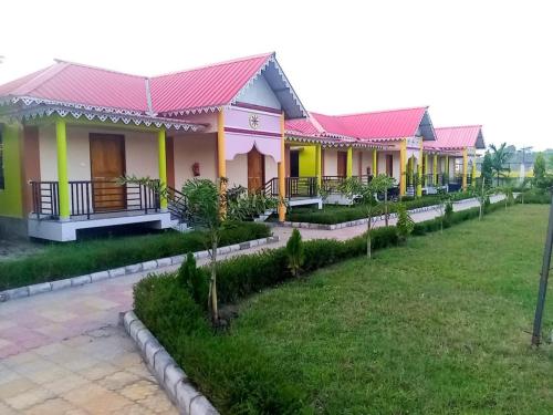 une rangée de maisons aux toits roses et jaunes dans l'établissement Kanchenjunga View Mansions By StayApart, à Lataguri